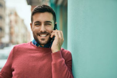 Genç İspanyol adam gülümsüyor. Şehirdeki akıllı telefondan konuşuyor..