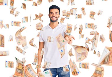 Genç, yakışıklı, günlük kıyafetler giyen, neşeli gülümseyen, yardım eli uzatan ve kabul gören İspanyol bir adam..