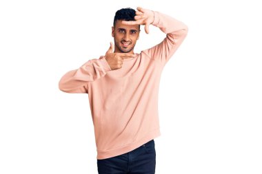 Gündelik kıyafetler giyen, gülümseyen, elleri ve parmakları gülen yüzlü, çerçeveli bir İspanyol. yaratıcılık ve fotoğrafçılık kavramı. 