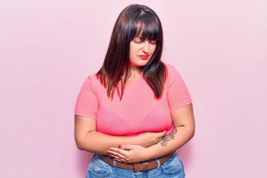 Genç ve cüsseli bir kadın elleri karnında günlük kıyafetler giyiyor çünkü hazımsızlık, acı verici bir hastalık kendini iyi hissetmiyor. Ağrı kavramı. 