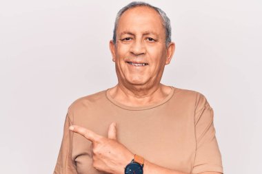 Gri saçlı, sıradan tişörtlü, neşeli gülümseyen, eli ve parmağı yana doğru olan son sınıf öğrencisi. 