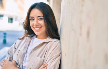 Genç İspanyol kadın gülümsüyor mutlu bir şekilde şehrin duvarına yaslanıyor..