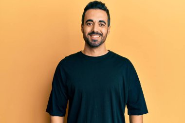 Yüzünde mutlu ve havalı bir gülümseme olan sıradan kıyafetler giyen genç İspanyol bir adam. şanslı kişi. 