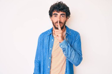 Kıvırcık saçlı ve sıradan kot ceket giyen yakışıklı genç adam sessiz olup dudaklarını öpmek istiyor. sessizlik ve gizli konsept. 