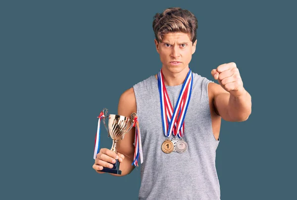 Jovem Homem Bonito Segurando Troféu Campeão Vestindo Medalhas Irritado Frustrado — Fotografia de Stock