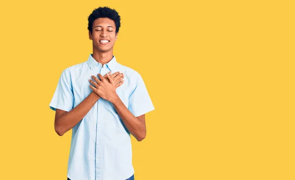 年轻的非洲裔美国人 身穿休闲装 双手胸前挂着微笑 闭着眼睛 脸上挂着感激的手势 健康概念 — 图库照片