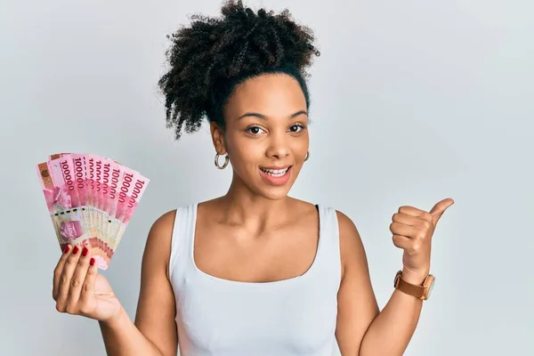 Mladá Africká Americká Dívka Držící Indonéské Rupiah Bankovky Ukazující Palcem — Stock fotografie