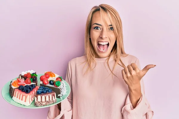 Beautiful Blonde Woman Holding Cake Slices Pointing Thumb Side Smiling — ストック写真