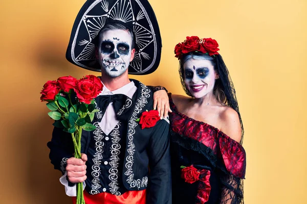若いですカップル身に着けているメキシコの日の死者の衣装を保持バラ正と幸せな立っていると笑顔で自信を持って笑顔を示す歯 — ストック写真