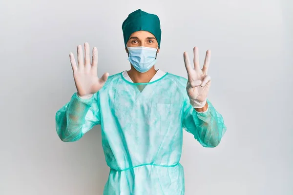 Fiatal Jóképű Férfi Sebész Egyenruhában Orvosi Maszkban Nyolcadik Ujjal Mutogatva — Stock Fotó