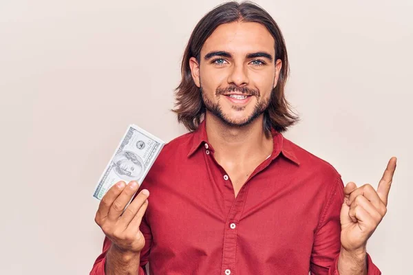 Jovem Homem Bonito Segurando Dólares Sorrindo Feliz Apontando Com Mão — Fotografia de Stock