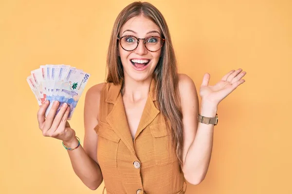 Young Blonde Girl Holding Colombian Pesos Celebrating Victory Happy Smile — Stock Photo, Image