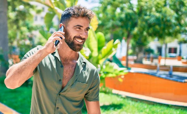 Ung Latinamerikansk Man Ler Glad Med Smartphone Promenader Parken — Stockfoto