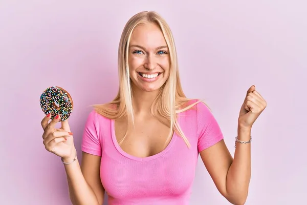 Jovem Loira Segurando Donut Gritando Orgulhoso Celebrando Vitória Sucesso Muito — Fotografia de Stock