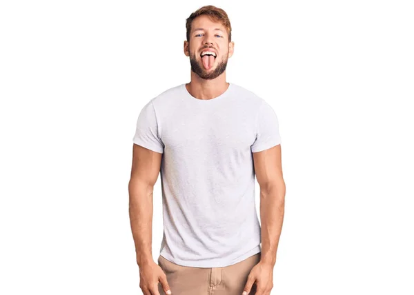 Jovem Caucasiano Vestindo Camiseta Branca Casual Colando Língua Feliz Com — Fotografia de Stock