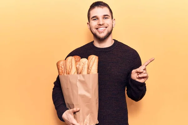 Jovem Homem Bonito Segurando Saco Papel Com Pão Sorrindo Feliz — Fotografia de Stock