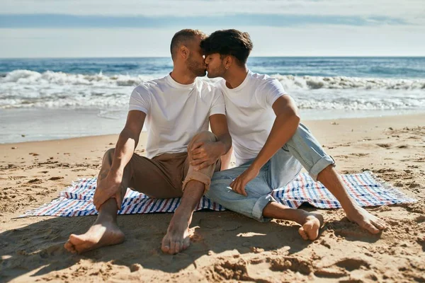 一对年轻的同性恋情侣坐在沙滩上接吻 — 图库照片