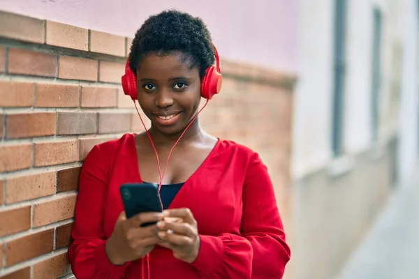 在城市里 年轻的非洲裔美国女人高兴地使用智能手机和耳机 — 图库照片