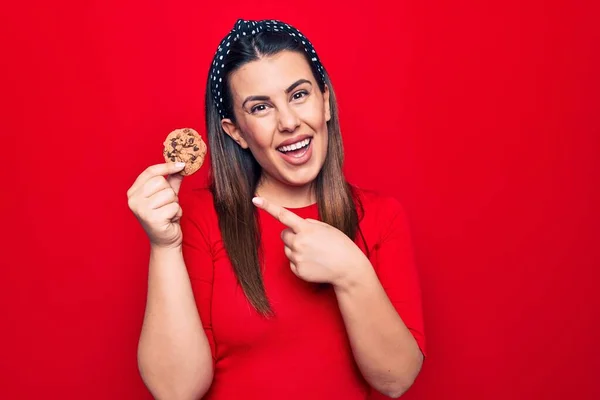 Junge Schöne Brünette Frau Mit Süßem Schokoladenkeks Über Isoliertem Rotem — Stockfoto