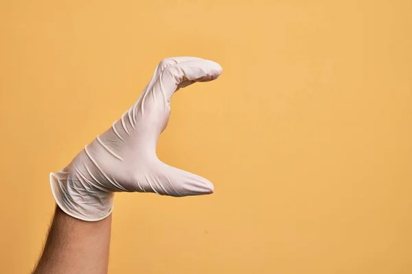 Mão Jovem Caucasiano Com Luva Médica Sobre Fundo Amarelo Isolado — Fotografia de Stock