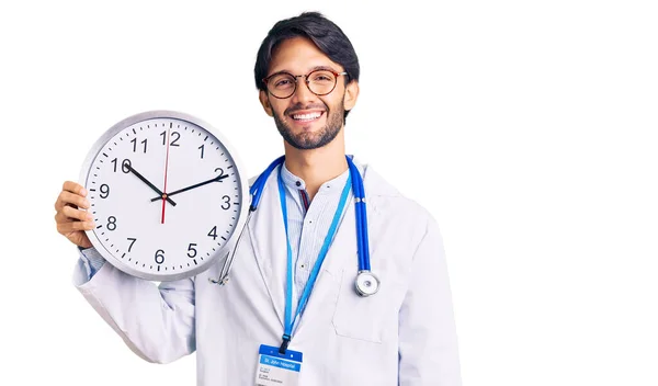 Bonito Homem Hispânico Vestindo Uniforme Médico Segurando Relógio Olhando Positivo — Fotografia de Stock