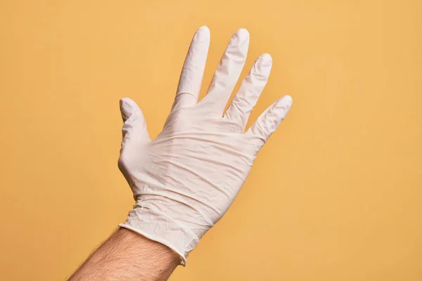 Mão Homem Jovem Caucasiano Com Luva Médica Sobre Fundo Amarelo — Fotografia de Stock