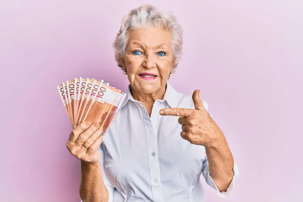 100ノルウェークローネ紙幣を保持しているシニアグレー髪女性笑顔幸せなポインティングとともに手と指 — ストック写真