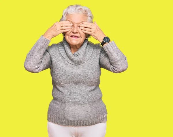 头发灰白的老年妇女穿着休闲地冬季毛衣 双手捂住眼睛 笑容满面 笑逐颜开 盲目概念 — 图库照片