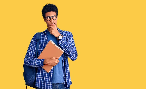 Joven Afroamericano Con Mochila Estudiantil Sosteniendo Libro Pensando Preocupado Por —  Fotos de Stock