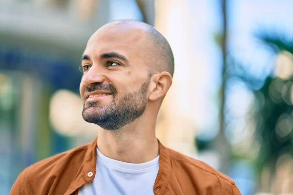 Young hispanic bald man smiling happy standing at the city.