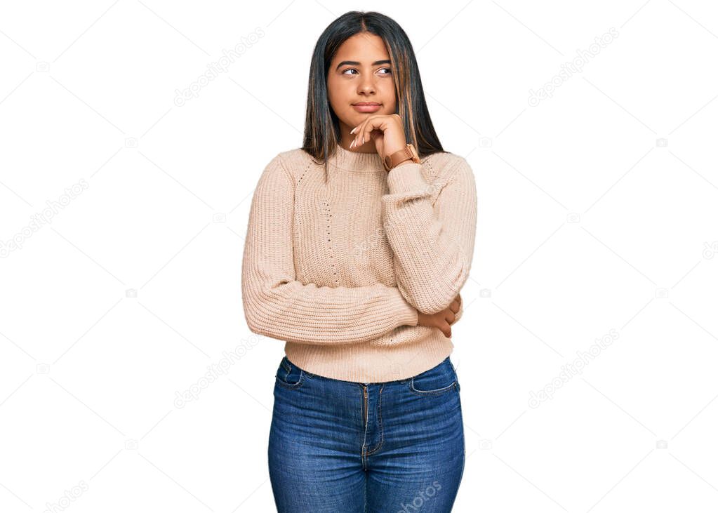 Young latin girl wearing wool winter sweater with hand on chin thinking about question, pensive expression. smiling and thoughtful face. doubt concept. 
