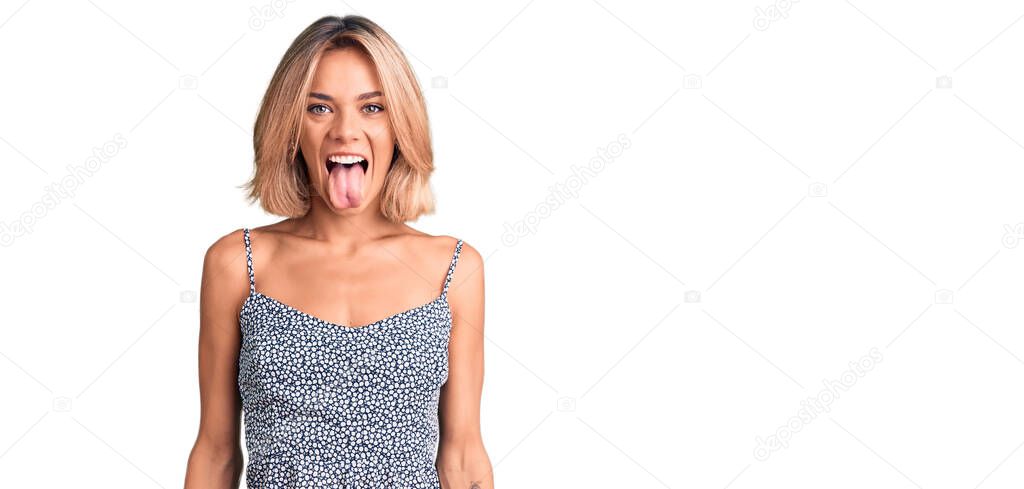 Beautiful caucasian woman wearing summer dress sticking tongue out happy with funny expression. emotion concept. 