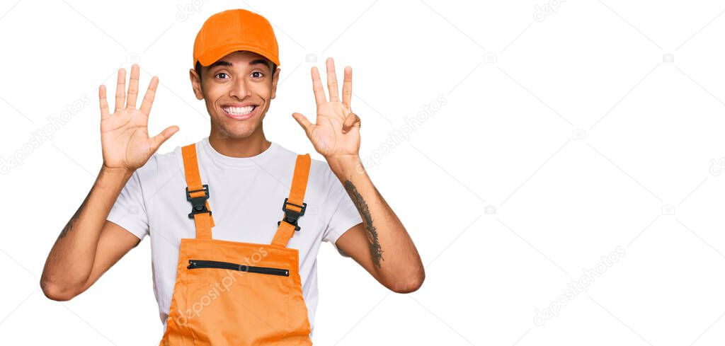 Young handsome african american man wearing handyman uniform showing and pointing up with fingers number nine while smiling confident and happy. 