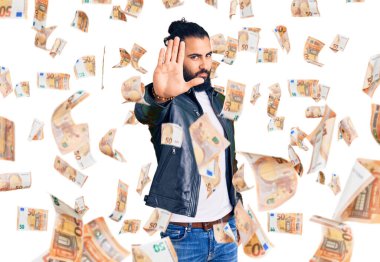 Deri ceket giyen genç bir Arap avucuyla şarkı söylemeyi kesiyor. Yüzünde olumsuz ve ciddi bir jest olan uyarı ifadesi.