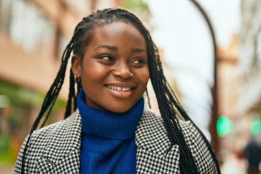 Genç Afrikalı Amerikalı iş kadını şehirde mutlu bir şekilde dikiliyor..