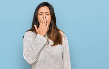 Gündelik kazak giyen güzel İspanyol kadın ağzıyla ağzını kapatmaktan sıkılmış. Huzursuz ve uykulu.. 