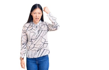 Genç, güzel, Çinli bir kadın, rahat gömleğini giyiyor kızgın ve kızgın. Öfkeyle bağırırken yumruğunu kaldırıyor. öfke ve agresif konsept. 