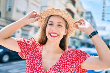 Genç sarışın kadın tatilde gülümsüyor. Mutlu bir şekilde caddede yürüyor.