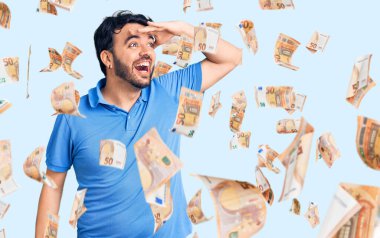 Gündelik kıyafetler giyen genç İspanyol adam çok mutlu ve gülümsüyor. Elleri başının üzerinde uzaklara bakıyor. arama kavramı.