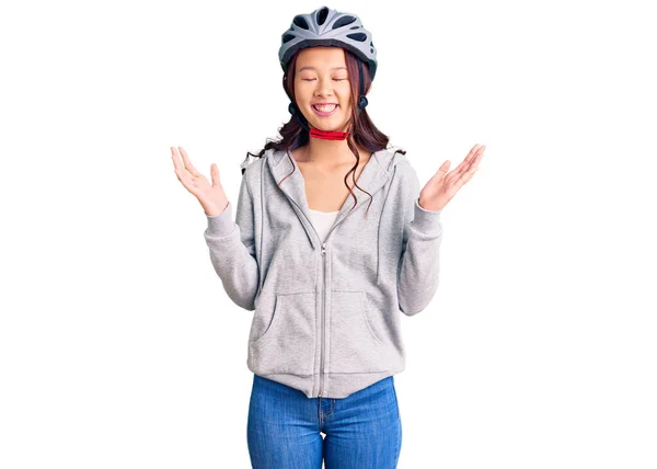 年轻美丽的中国姑娘戴着自行车头盔 抱着胳膊 紧闭双眼 兴奋地尖叫着 庆祝着胜利的到来 获奖者概念 — 图库照片