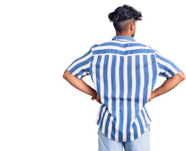 Gündelik kıyafetler giyen genç İspanyol adam kolları vücudunda geriye doğru bakıyor. 