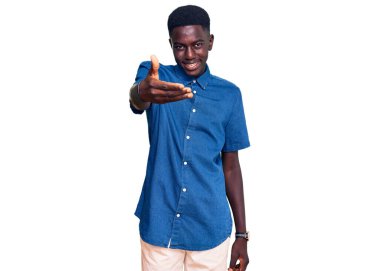 Genç Afrikalı Amerikalı günlük kıyafetler giymiş neşeli gülümseyerek yardım eli uzatıyor ve kabul ediyor.. 