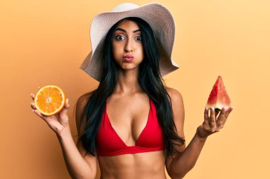 Karpuz yiyen güzel İspanyol kadın ve komik suratlı turuncu yanaklar. Ağzı havayla şişer, havayı yakalar.. 