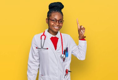 Genç Afro-Amerikan kadın doktor üniforması giyiyor ve steteskop başarılı bir fikri işaret ediyor. Heyecanlı ve mutlu. Bir numara.. 