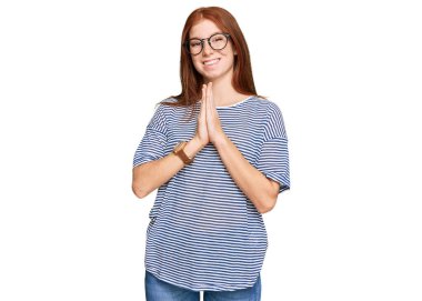 Gündelik kıyafetler giyen, gözlüklü genç bir kadın ellerinin birarada dua ederek af diliyor kendinden emin bir şekilde gülümsüyor.. 