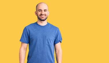 Yüzünde mutlu ve havalı bir gülümseme olan sıradan tişörtler giyen genç yakışıklı bir adam. şanslı kişi. 