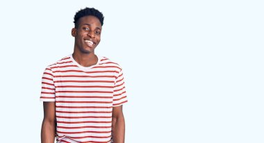 Genç Afro-Amerikalı sıradan kıyafetler giymiş, kameraya seksi bir ifadeyle bakıyor, neşeli ve mutlu bir yüzle.. 