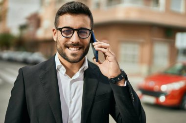 Genç İspanyol işadamı gülümsüyor. Şehirdeki akıllı telefondan mutlu bir şekilde konuşuyor..