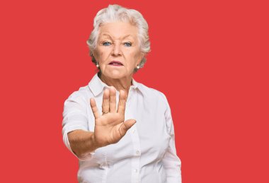 Gri saçlı, günlük kıyafetler giyen yaşlı kadın avucunun içi gibi şarkı söylemeyi kesiyor. Yüzünde olumsuz ve ciddi bir jest olan uyarı ifadesi. 