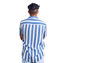 Gündelik kıyafetler giyen genç İspanyol adam arkasını dönüp kollarını kavuşturarak başka tarafa bakıyor. 